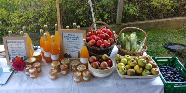 Etal de marché avec les produits de la ferme familiale du potager joyeux : jus de pomme, fruits, légumes, miels