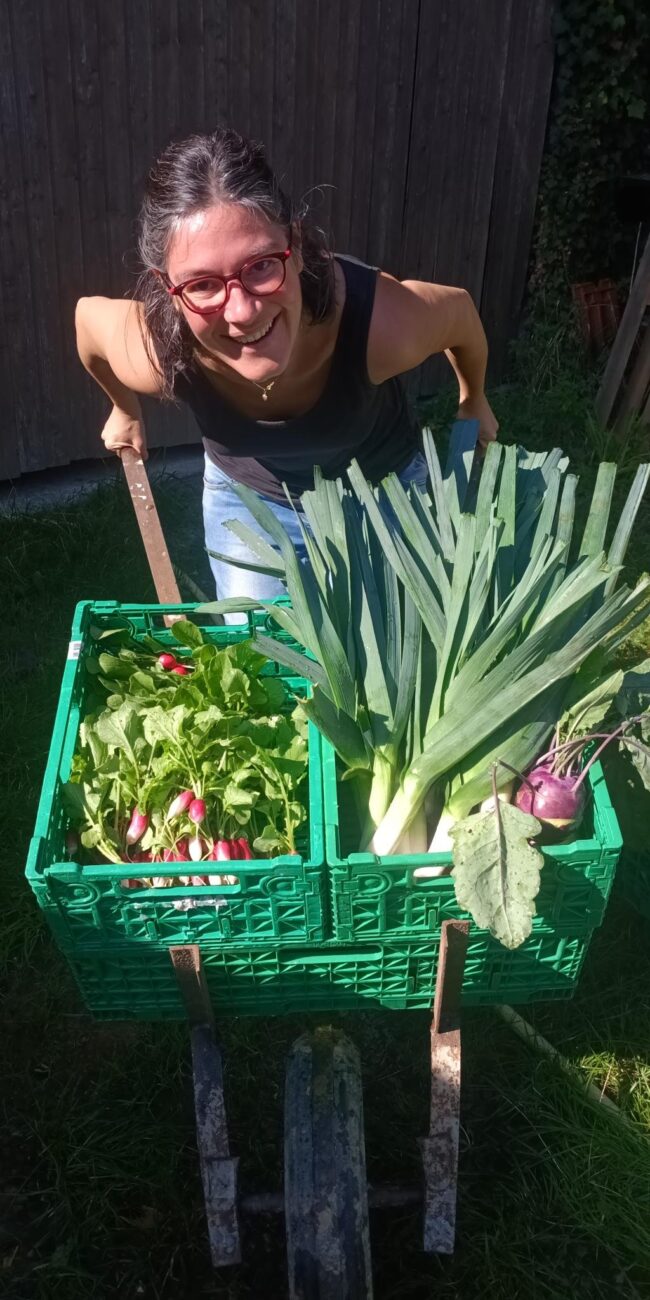 Mathilde présente la récolte de légumes du potager joyeux dans une brouette